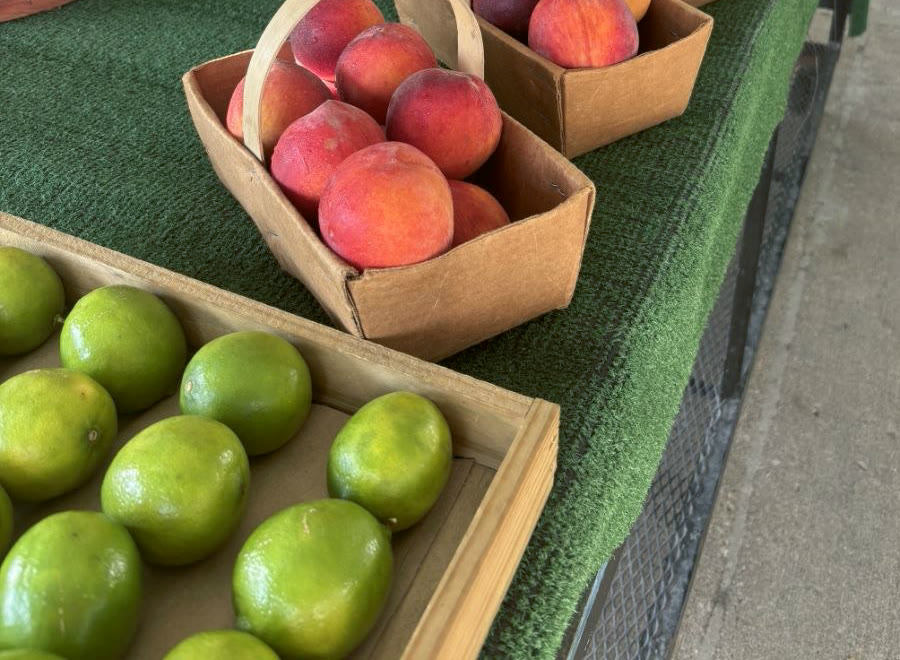 Ripe peaches in baskets beside limes at the stand.